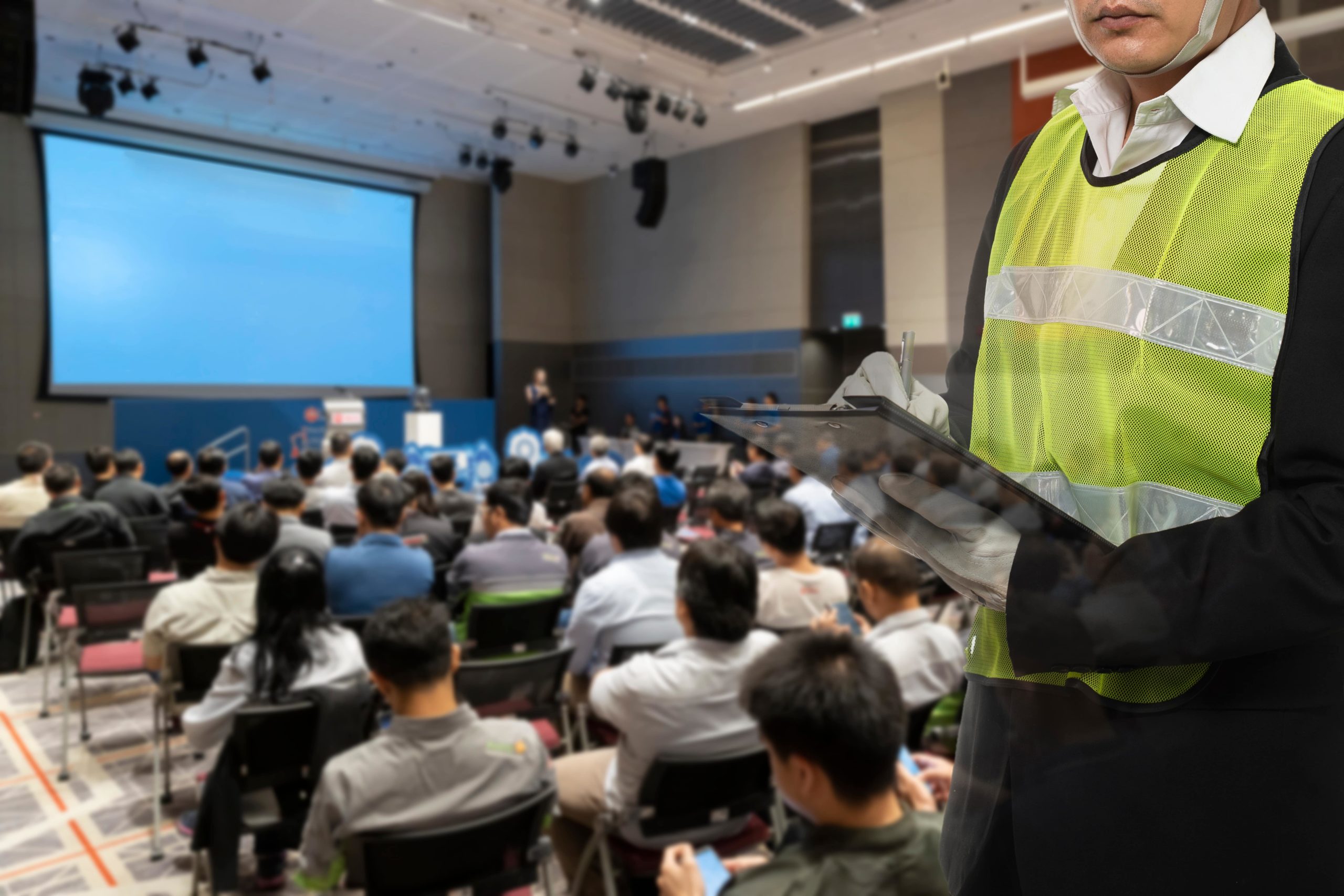 Corporate employees sitting in a large conference room looking at a projector screen.