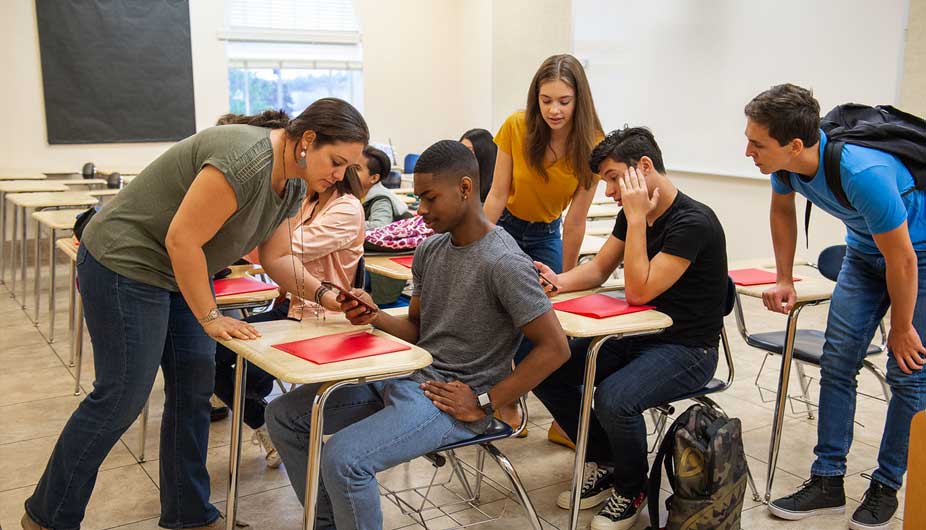 Teacher with students looking at phone