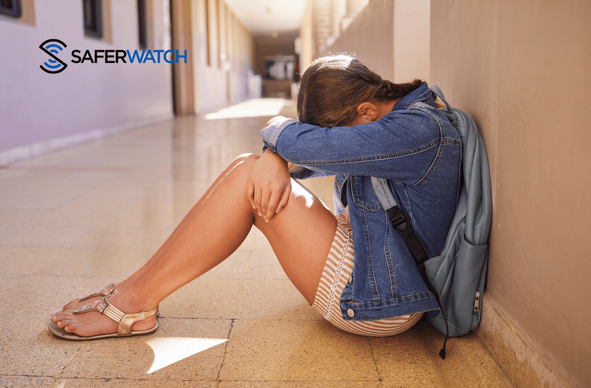 young girl with her head down in a school hallway - SaferWatch