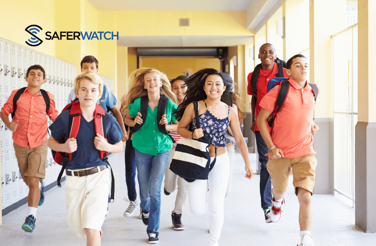 Happy students running in a school campus hallway - SaferWatch